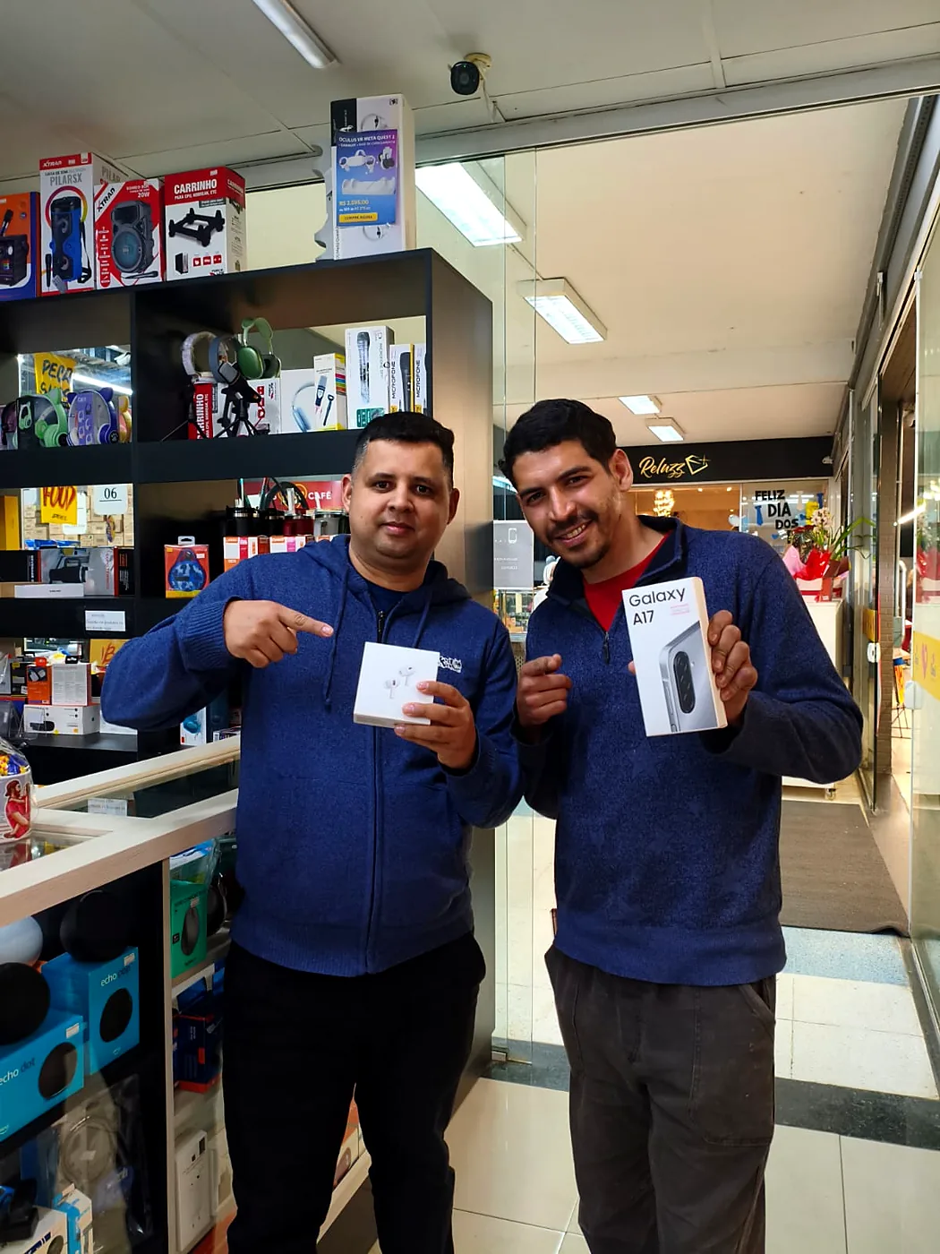 Cliente sorrindo com a caixa de um Samsung Galaxy A17 ao lado de Junior