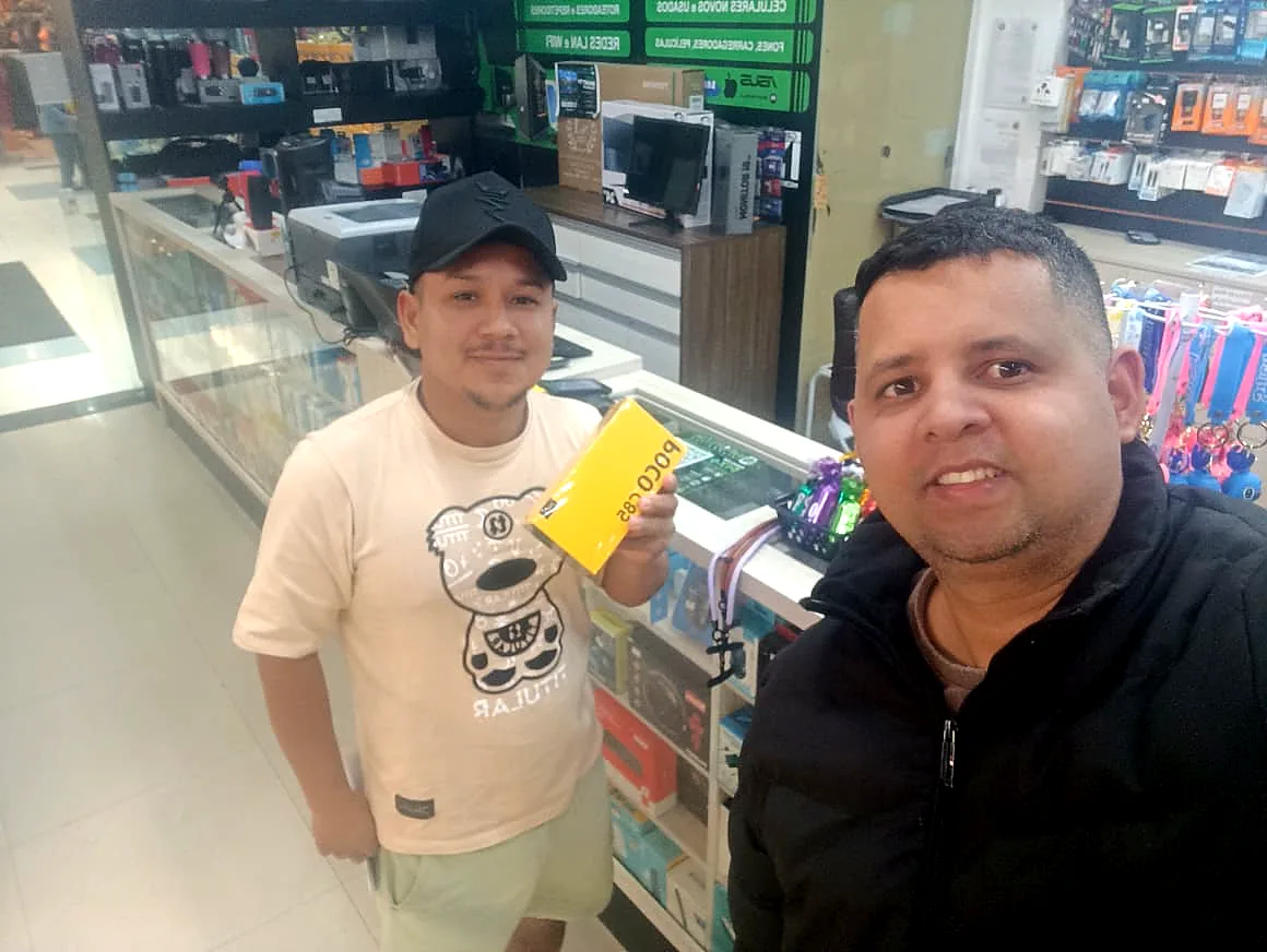 Cliente com a caixa amarela de um POCO C85 no balcão da Infotech